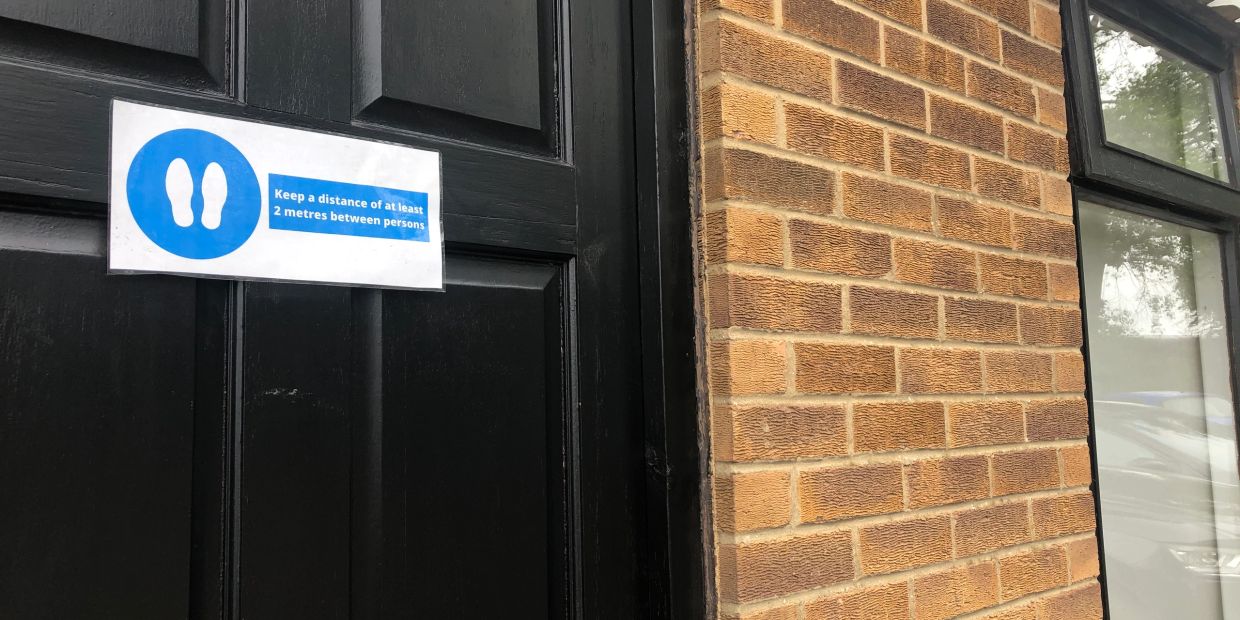 Sign on door instructing to keep 2 metres distance between persons.