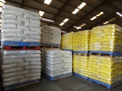 Stacks of white and yellow bagged goods on pallets in a warehouse.