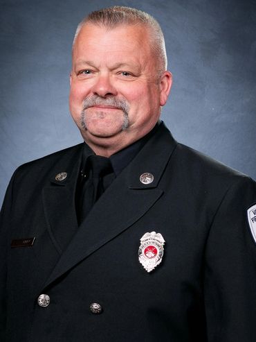 Portrait of a firefighter in uniform with badges and insignia.