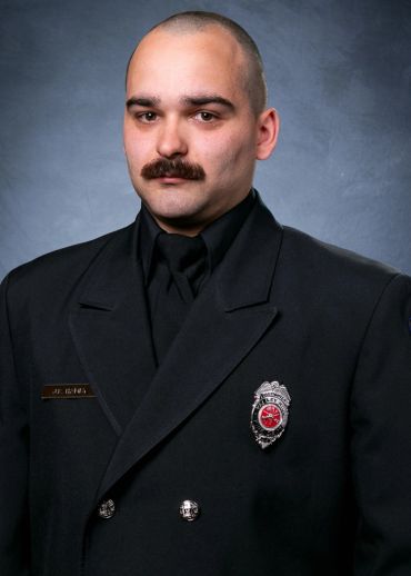 Portrait of a man in a formal uniform with a badge and name tag.
