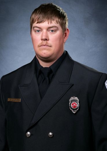 Portrait of a serious firefighter in uniform against a gray backdrop.
