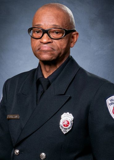 Portrait of a fire department officer in uniform with badges and glasses.