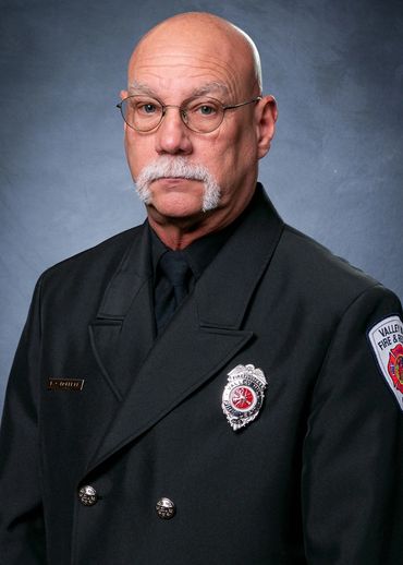 Portrait of a serious firefighter in uniform with a distinctive mustache.