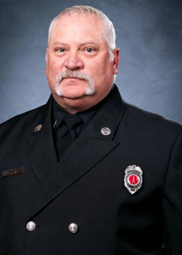 Portrait of a uniformed firefighter with a distinctive mustache.
