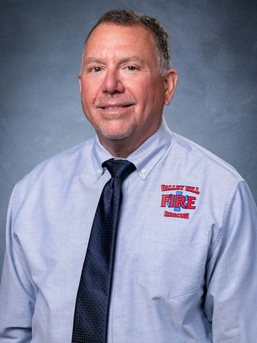 Man in a light blue shirt with 'Waverly Hill Fire Rescue' logo and dark tie.
