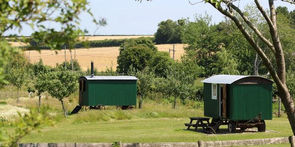 Distance view of glamping holidays shepherds huts in lush green Dorset Countryside at Rustic Stays