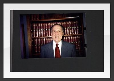 Portrait of a man in a suit standing in front of a law bookcase.