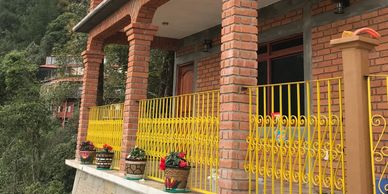 A brick house with a yellow railing and flower pots on the balcony.