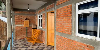 Cozy brick balcony with wooden door and rocking chair under ceiling light.