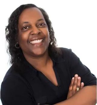 A smiling woman with crossed arms wearing a black shirt.