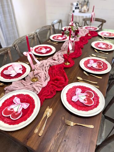 Valentine-themed dining table with cherry plates and red candles.