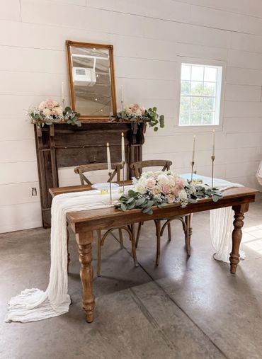 Rustic wedding table with floral arrangements and candles.