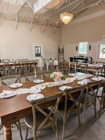 Rustic wooden tables set for an elegant event in a spacious venue.