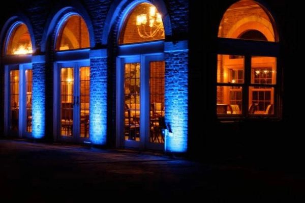 Building facade with blue uplighting and warm interior lights at night.