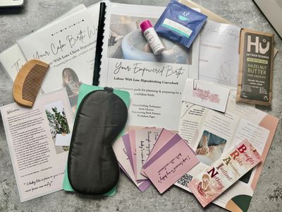 Self-care products including a sleep mask, comb, and chocolate bar on a table.