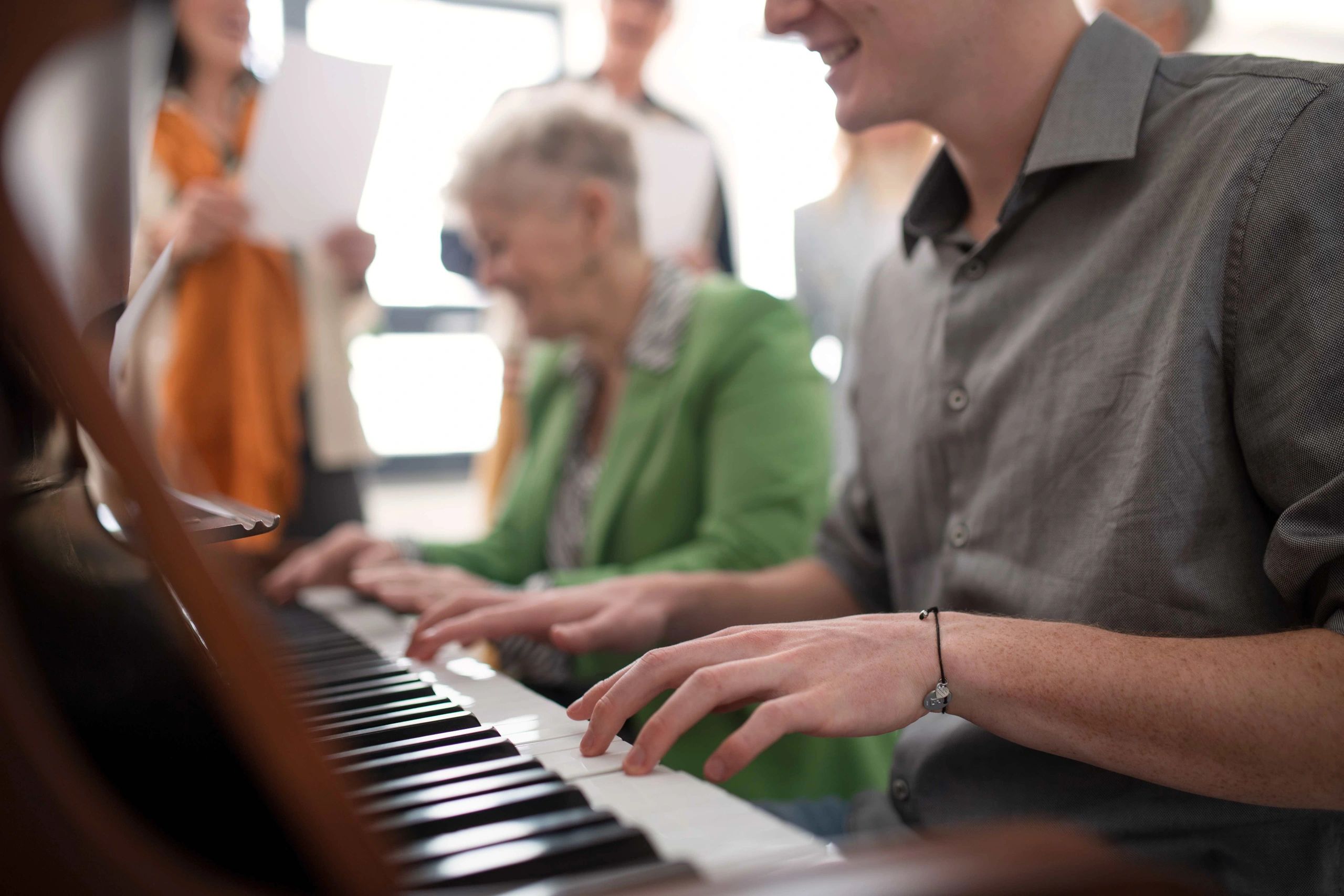 Group of adults gather around piano at St Louis group music lessons for the community