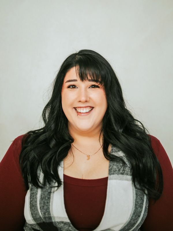 Smiling woman with long black hair and a lip piercing.