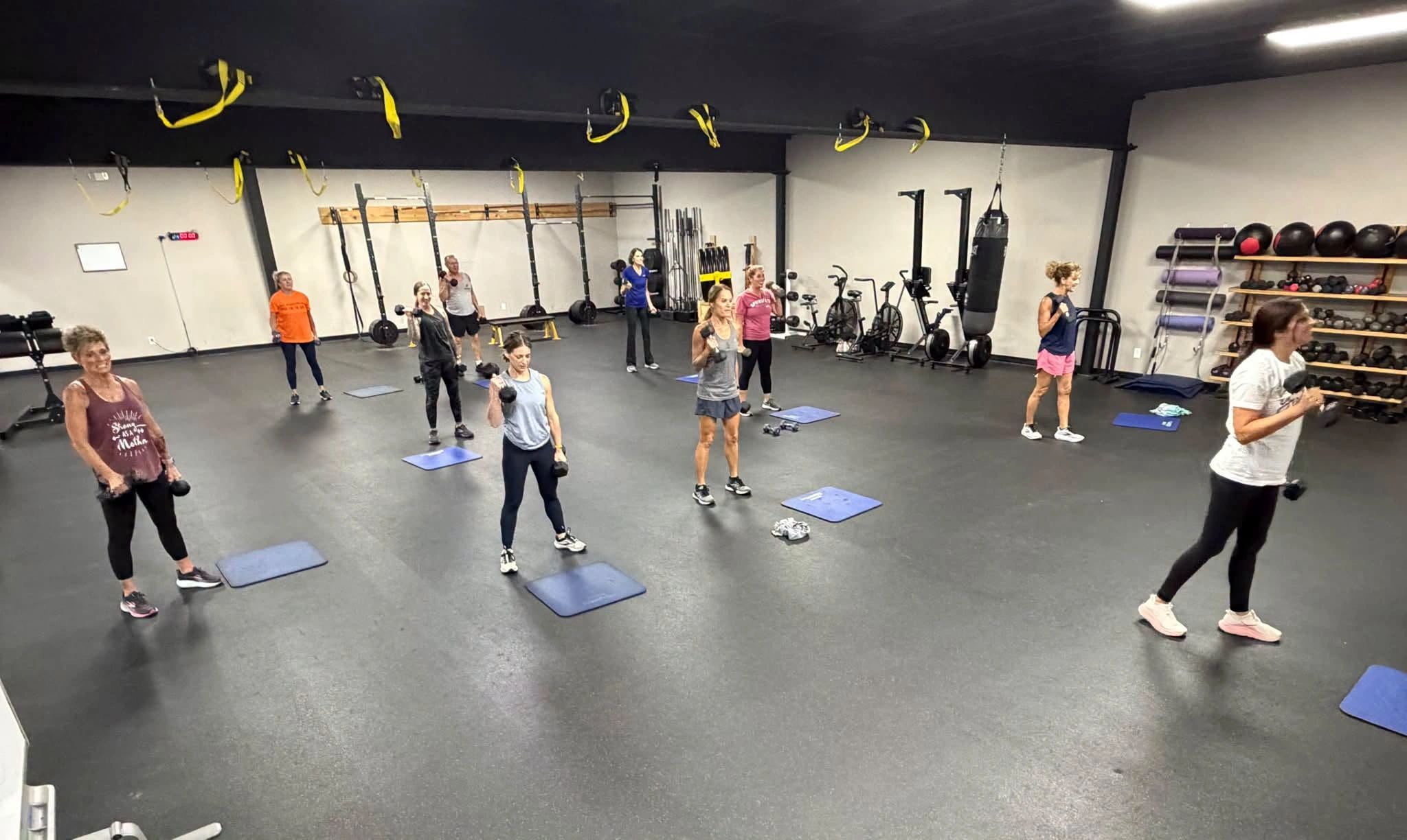 Group workout class with members exercising on mats in the gym
