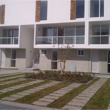 Modern white townhouse with garden and stone pathway.