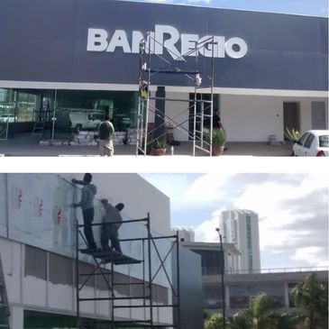 Workers installing or repairing signage on a building facade.