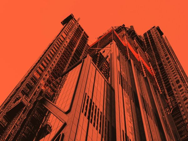 A towering modern skyscraper under construction with an orange filter.