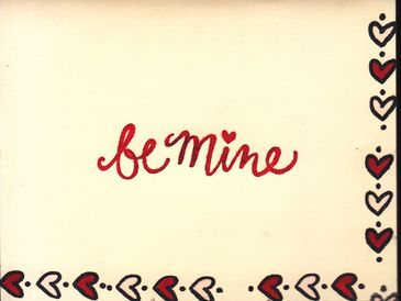 Handwritten 'be mine' with heart decorations on cream background.