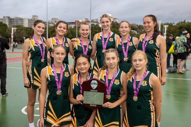 Girls' basketball team proudly holding a championship plaque with medals outdoors.
