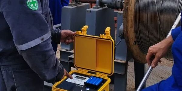 Two workers handling yellow equipment case.