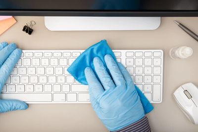 Gloved hands cleaning keyboard for Covid-19.