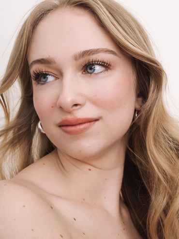 Close-up portrait of a young woman with blonde hair and natural makeup.