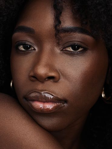 Close-up portrait of a woman with glossy lips and curly hair.