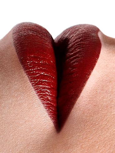 Close-up of lips painted with dark red lipstick forming a heart shape.