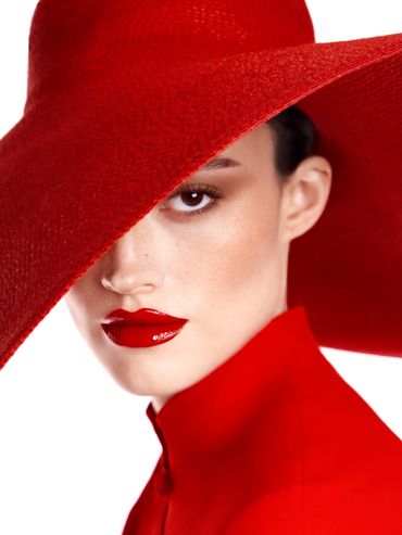 Woman wearing a large red hat and matching red lipstick and outfit.