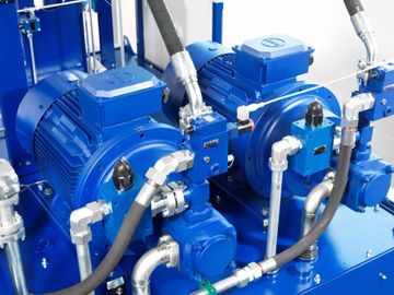 Two large blue industrial electric motors with connected pipes and hoses.