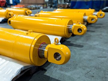 A row of yellow hydraulic cylinders in an industrial setting.