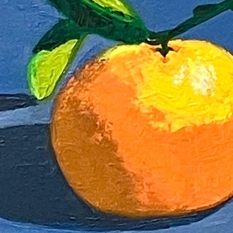 Close-up of a vibrant orange fruit with green leaves against a blue background.
