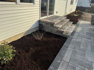 Newly mulched garden bed and stone patio steps at a house.