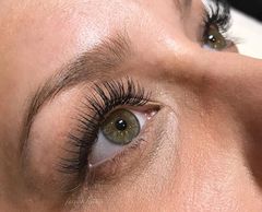 Close-up of an eye with long, thick eyelashes and groomed eyebrows.