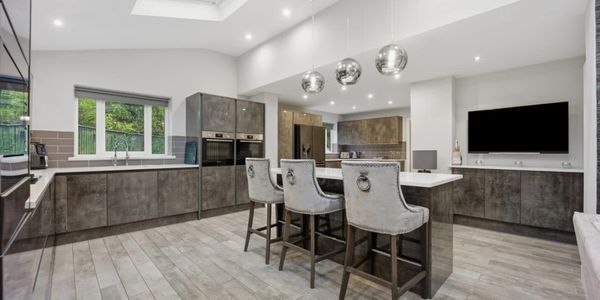 Modern kitchen with gray cabinets, island seating, and metallic pendant lights.