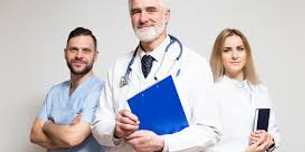 Three healthcare professionals posing confidently together against a white background.