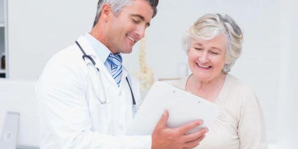 Doctor discussing medical information with a smiling elderly woman.