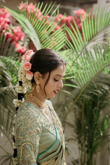 Woman in traditional attire with floral hair accessories and gold jewelry.