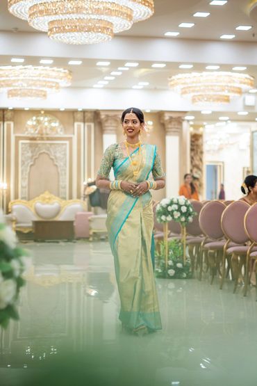 Woman dressed in traditional Indian saree walking in an elegant event hall.