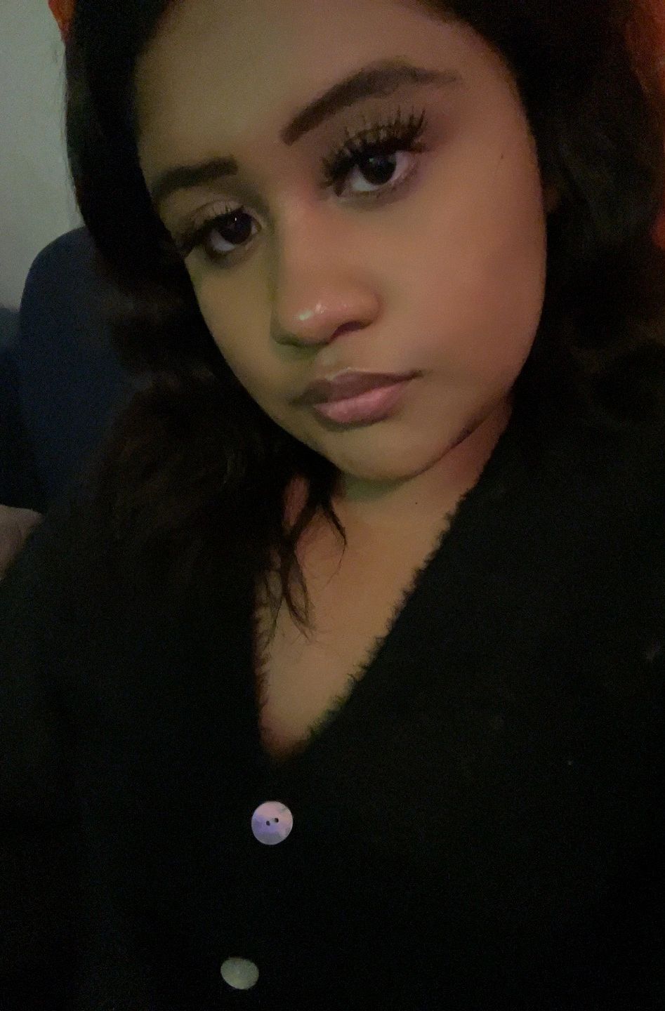 Close-up selfie of a young woman with dark hair wearing a black top.