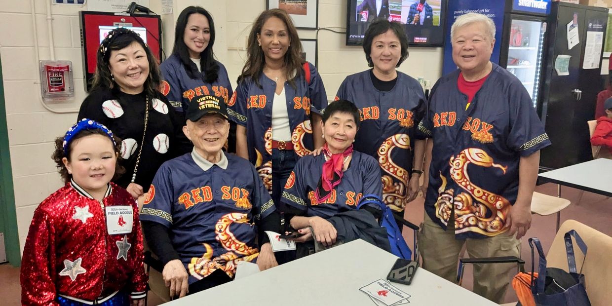 A group wearing Red Sox jerseys posing indoors around a table.