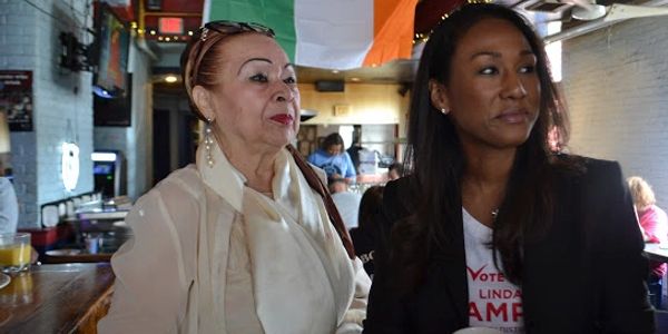 Two women sitting at a bar with an Irish flag in the background.