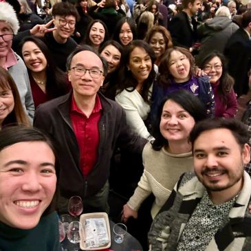 A diverse group of people smiling and taking a selfie at a social gathering.