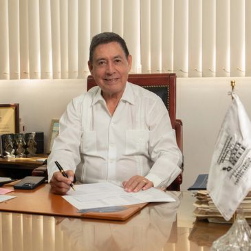 Man in white shirt signing documents at desk in office.