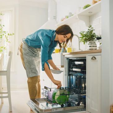 A woman is putting dishes in the dishwasher.