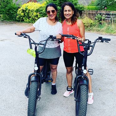 two female friends smiling on e-bikes